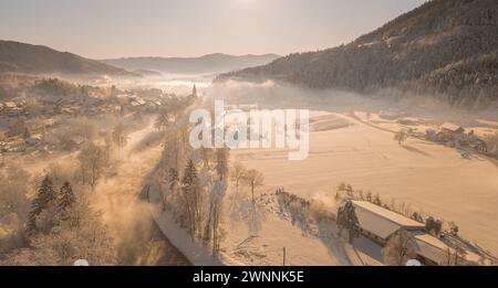 Splendido villaggio di Ljubno ob Savinji, sede di gare femminili di salto con gli sci. Panorama invernale dall'alto del villaggio la mattina presto. Il sole sorge sopra Foto Stock