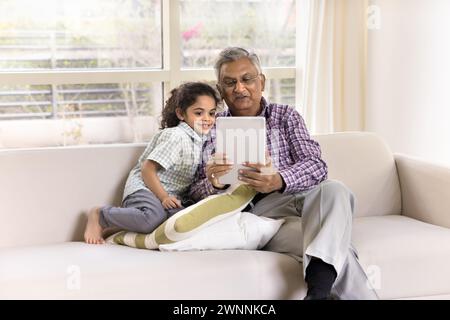 Nonno indiano positivo che mostra applicazione di apprendimento online a nipotino piccolo Foto Stock