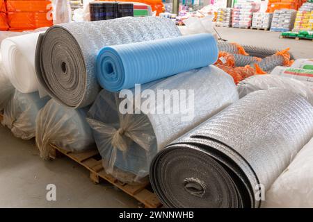 Diversi materiali isolanti in rotoli per la vendita in magazzino. Grandi rotoli in polietilene laminato in alluminio termico per rivestimenti di case e buildi Foto Stock