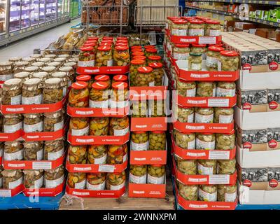 Italia - 02 marzo 2024: Verdure, olive, carciofi e funghi in olio in vasetti di vetro impilati su pallet in vendita in discount italiano Foto Stock