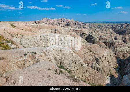 I turisti si trovano su un affioramento roccioso che si affaccia su strati colorati di roccia sedimentaria nel Badlands National Park nel South Dakota, Stati Uniti Foto Stock