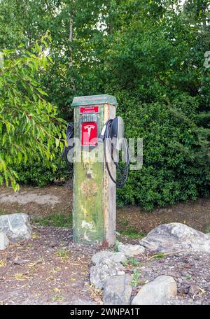 Cardrona, nuova Zelanda- 13 dicembre 2023: Una stazione di ricarica per veicoli elettrici Tesla, montata su un palo rustico, si erge in mezzo a una vegetazione lussureggiante, offrendo un b Foto Stock