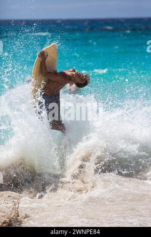 La gente del posto cavalca le onde su una spiaggia di sabbia bianca alle Hawaii. Foto Stock