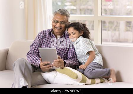 Felice nonno indiano e piccola nipote ragazza che usa il tablet Foto Stock