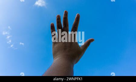 Aprite le palme o date un cartello per smettere di puntare verso il cielo. Sullo sfondo di un cielo blu brillante al mattino Foto Stock