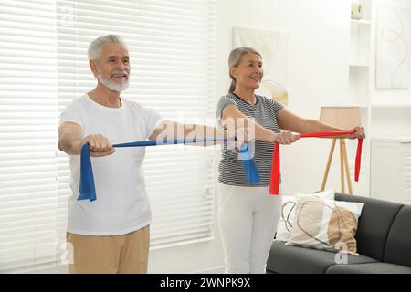 Coppia senior che fa esercizio fisico con fasce elastiche fitness a casa Foto Stock