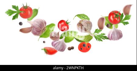 Aglio fresco, grani di pepe, pomodoro ed erbe che cadono su sfondo bianco Foto Stock