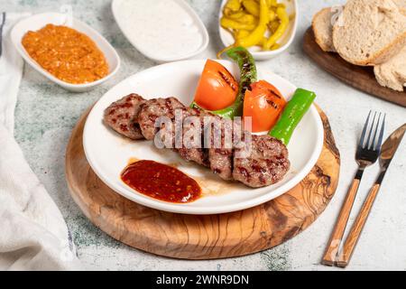 Polpette di carne alla griglia. Con pomodori, peperoni, antipasti e salsa speciale. Polpette turche su un piatto Foto Stock