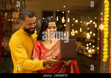 Giovane marito indiano che regala alla moglie preziosi gioielli in occasione del Diwali o dell'anniversario di matrimonio. Marito e moglie vestite in abiti tradizionali su festiva Foto Stock