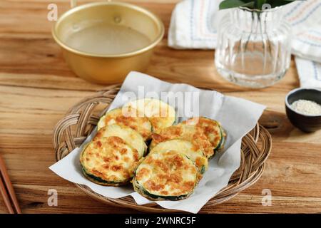 Hobak Jeon o zucchine fritte in padella coreana servite con Makgeolli. Su tavolo di legno Foto Stock