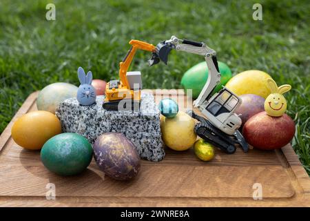 Offerta per le vacanze primaverili di Pasqua. cartolina di aziende edili. modelli giocattolo di attrezzature da costruzione - escavatori e uova colorate Foto Stock