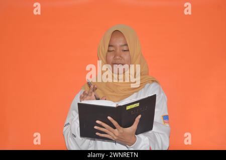 16 settembre 2023, foto di una donna musulmana che porta un libro, Wonosobo, Indonesia Foto Stock