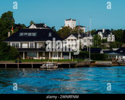 Vista sul lungomare su case bianche su una riva nel fiordo di Oslo. Case indipendenti norvegesi Foto Stock