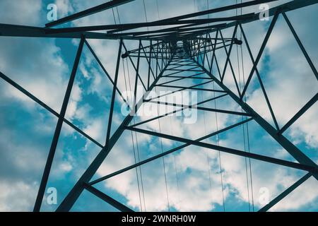 Torre di distribuzione dell'elettricità dal basso, linee elettriche ad alta tensione sotto il cielo nuvoloso. Vista ad angolo basso. Foto Stock