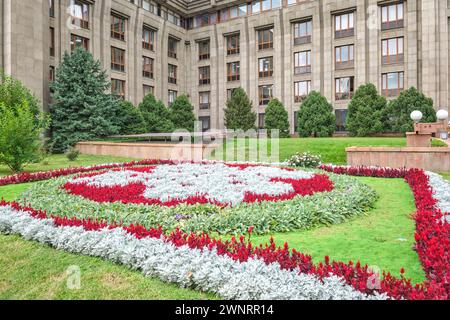 Un colorato letto di fiori nel cortile anteriore della Banca Nazionale della Repubblica del Kazakistan, formalmente l'edificio del parlamento. Ad Almaty, Kazakistan Foto Stock