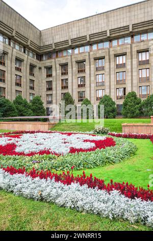 Un colorato letto di fiori nel cortile anteriore della Banca Nazionale della Repubblica del Kazakistan, formalmente l'edificio del parlamento. Ad Almaty, Kazakistan Foto Stock