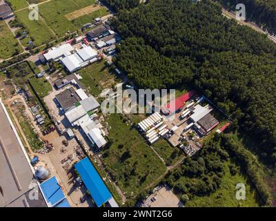 Un'immagine in alto che cattura un'ampia area industriale, mostrando fabbriche, magazzini e vegetazione circostante sotto un cielo limpido. Foto Stock