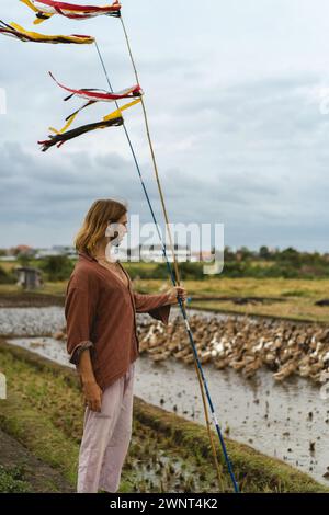 Uomo dai capelli lunghi in una fattoria di anatre. Anatre in un campo di riso Bali Foto Stock