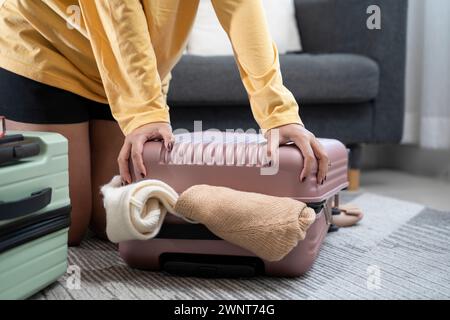 Giovane donna asiatica che impilava vestiti e nel caso della borsa, cercando di portare bagagli a mano. Foto Stock