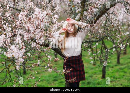 Primavera in arrivo. Bella donna che cammina nel giardino degli alberi primaverili. Concetti di stile di vita per le persone di bellezza. Foto Stock