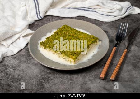 Kadayif freddo con pistacchio. kadayıf dessert al latte con pistacchi su sfondo scuro. Nome locale soğuk kadayıf tatlısı Foto Stock