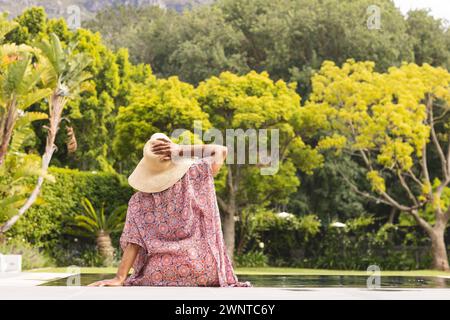 Una donna birazziale senior gode di un momento tranquillo in piscina, con spazio per fotocopie Foto Stock
