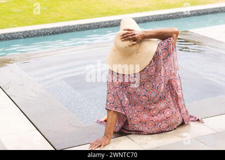 Una donna birazziale senior si gode un momento vicino alla piscina con spazio fotocopie Foto Stock