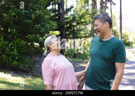 Donna e uomo birazziali senior condividono una risata all'aperto Foto Stock