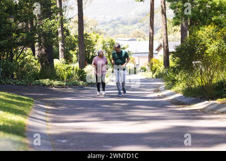 Una coppia birazziale senior si gode una piacevole passeggiata in un lussureggiante parco verde con spazio per fotocopie Foto Stock