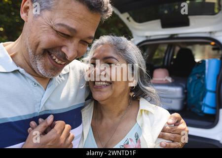 La coppia birazziale senior condivide un momento di gioia, con l'uomo che abbraccia la donna Foto Stock