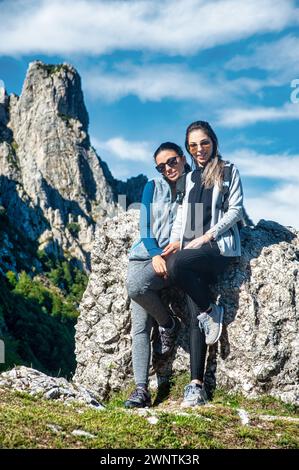 Due giovani amici si abbracciano durante una pausa mentre camminano in montagna Foto Stock