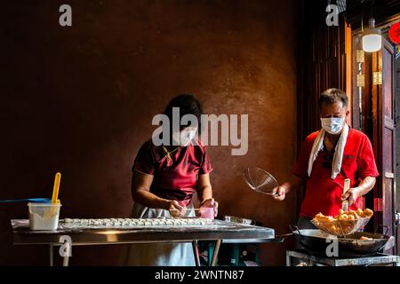 Jomtien, Thailandia, 10 febbraio 2024: Chakngeaw Chinese Village. Una coppia prepara lo youtiao, una lunga striscia di impasto di farina di grano dorata fritta in profondità. Foto Stock