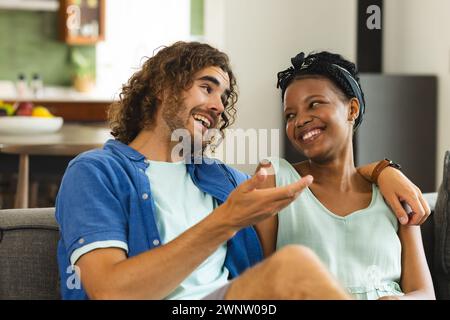 Coppia eterogenea, giovane uomo caucasico e donna afroamericana condividono un momento di gioia su un divano Foto Stock