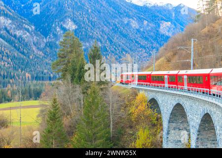 Treno passeggeri rosso sulla ferrovia Retica nel Canton Graubunden, Svizzera, in autunno Foto Stock