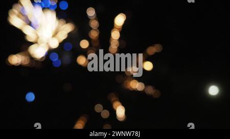 I fuochi d'artificio bokeh di Capodanno. Scintille sfocate multicolore sul cielo notturno nero. Sfondo nero con cerchi astratti. Una bella luce Foto Stock