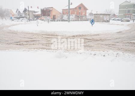 Sremska Mitrovica, Serbia, 12 dicembre 2021 Una biforcazione o un fianco da una rotonda. Piste da neve sul lato della strada. Maltempo. Guida difficile Foto Stock