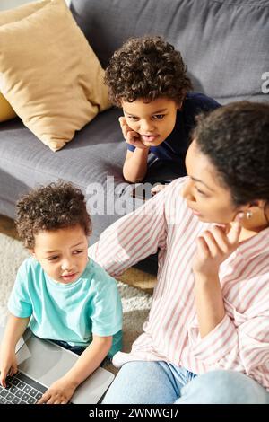 bella madre afroamericana che si diverte con i suoi adorabili figli in salotto Foto Stock