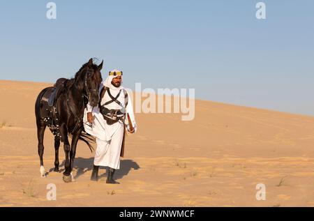 Ritratto di un uomo saudita con il suo stallone nero Foto Stock