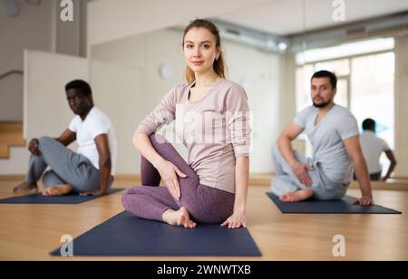 Persone che esercitano signore dei pesci asana in palestra Foto Stock