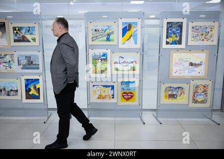 Kiev, Ucraina. 4 marzo 2024. Il lavoratore della centrale nucleare cammina vicino ai disegni dei bambini sull'occupazione della stazione di Zaporizhzhia in un evento dedicato a commemorare il secondo anniversario dell'occupazione da parte delle forze armate russe della centrale nucleare di Zaporizhzhia, a Kiev. La centrale nucleare di Zaporizhzhya fu occupata dalle truppe russe il 4 marzo 2022. Credito: SOPA Images Limited/Alamy Live News Foto Stock