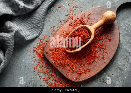 Macchie di zafferano essiccate in cucchiaio su fondo rustico, spezie ed erbe (Crocus sativus) Foto Stock