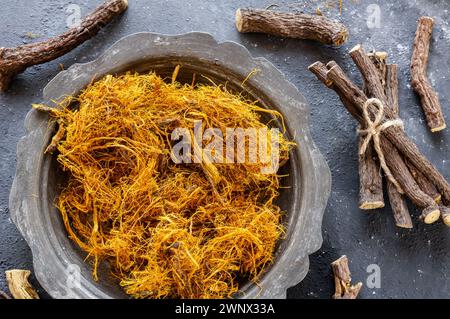 Radice di liquirizia, fibra di liquirizia in ciotola su fondo rustico ( glycyrrhiza glabra ) Foto Stock