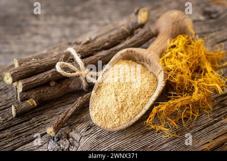 Radice di liquirizia, fibra di liquirizia e polvere o ciotola in cucchiaio su fondo rustico ( glycyrrhiza glabra ) Foto Stock