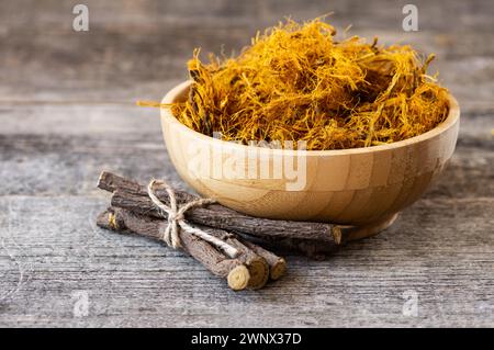 Radice di liquirizia, fibra di liquirizia in ciotola su fondo rustico ( glycyrrhiza glabra ) Foto Stock