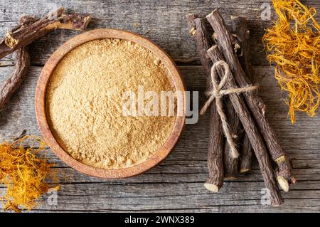 Radice di liquirizia, fibra di liquirizia e polvere o ciotola in cucchiaio su fondo rustico ( glycyrrhiza glabra ) Foto Stock