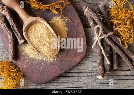 Radice di liquirizia, fibra di liquirizia e polvere o ciotola in cucchiaio su fondo rustico ( glycyrrhiza glabra ) Foto Stock