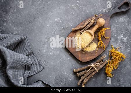 Radice di liquirizia, fibra di liquirizia e polvere o ciotola in cucchiaio su fondo rustico ( glycyrrhiza glabra ) Foto Stock