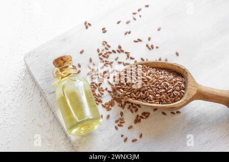 Bottiglia di vetro di semi di lino o olio di lino con semi di lino su tavola rustica, olio di fondo di fibra alimentare Foto Stock