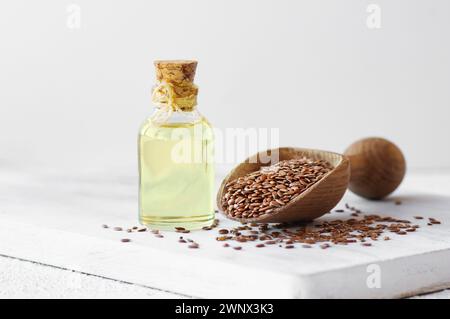 Bottiglia di vetro di semi di lino o olio di lino con semi di lino su tavola rustica, olio di fondo di fibra alimentare Foto Stock