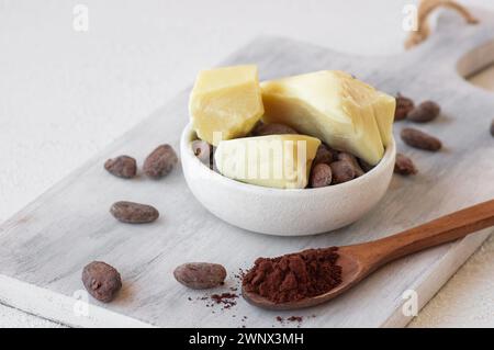 Burro di cacao o olio solido di fagioli di cacao e fagioli di cacao crudi sullo sfondo rustico, olio naturale sano Foto Stock